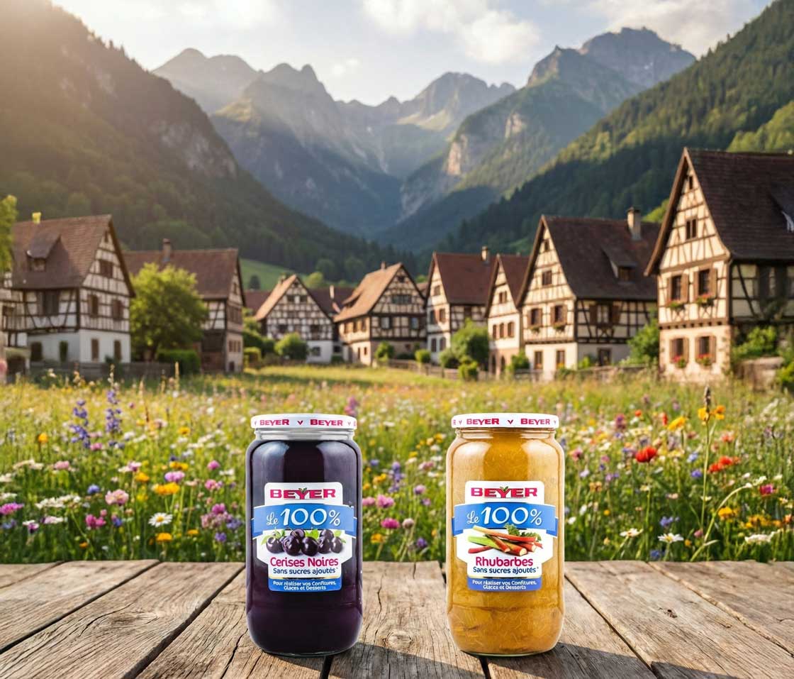 Un pot de purée 100% fruits Beyer, posé dans la neige devant un chalet et un sapin de Noël qui brille.